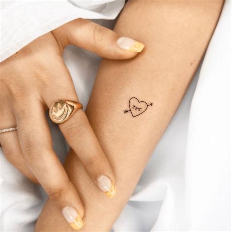 Minimalistic style heart and arrow tattoo located on