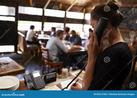 Young Woman Taking a Reservation by Phone at a Restaurant Stock Photo ...