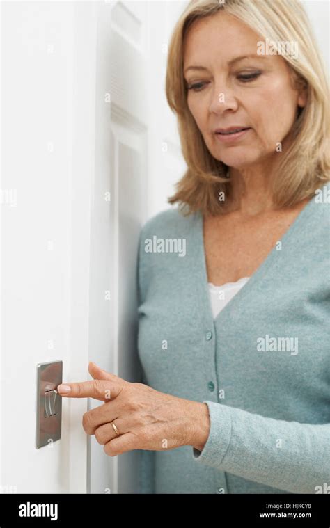 Mature Woman Turning Off Light Switch At Home Stock Photo - Alamy