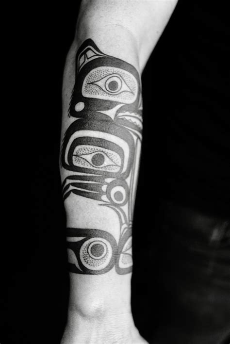 a man with a tattoo on his arm and hand holding an object in the shape of a totem