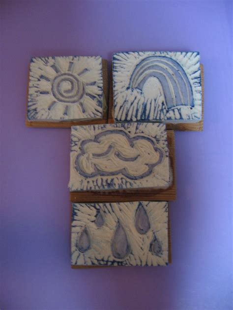 three square tiles with designs on them against a purple wall, one has a rainbow and the other ...