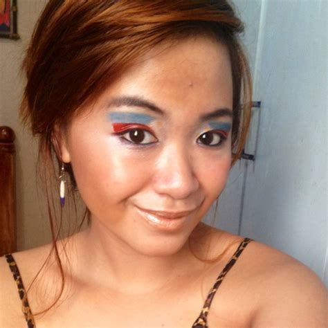 a woman with blue and red eyeliners on her face smiling at the camera