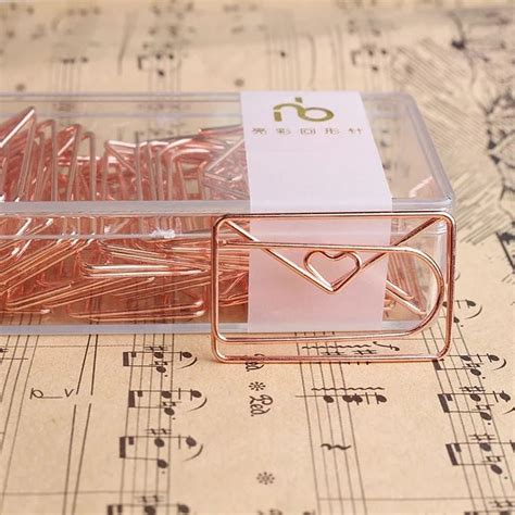 there is a box with some pink paper clips in it on top of sheet music