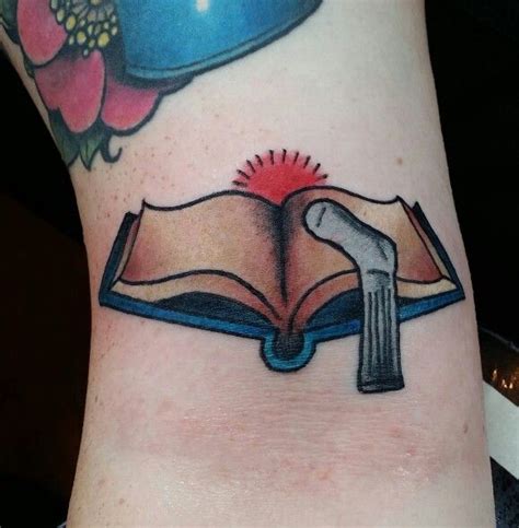 an open book with a hammer on top of it and a blue lamp above it