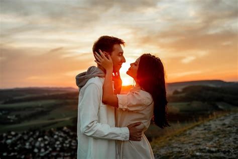 Premium Photo | A couple in love, a guy and a girl are standing on a mountain at sunset hugging ...