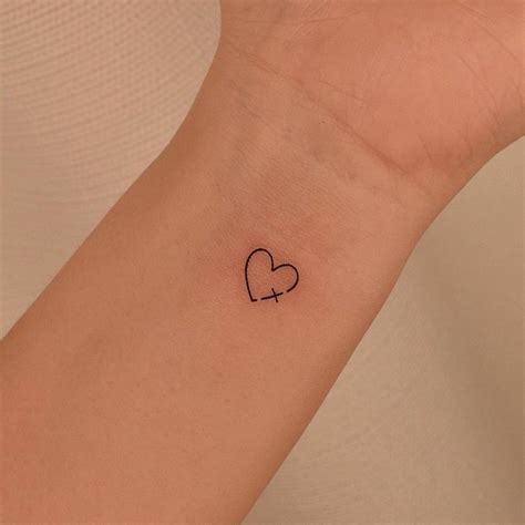 Minimalist cross and heart tattoo on the wrist