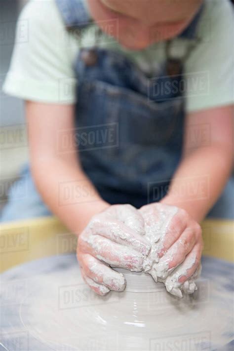 Boy shaping clay on potter's wheel - Stock Photo - Dissolve