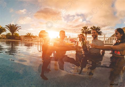 Happy friends cheering with champagne in pool party at sunset - stock ...