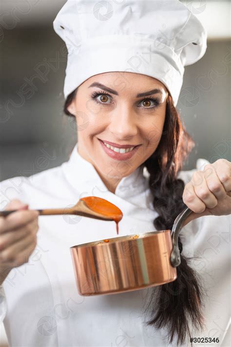 Professional female chef holds a wooden spoon with orange sauce - stock photo 3025346 | Crushpixel