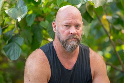 Casual Man in a Tank Top Posing Outdoors in a Garden. Guy is in 50`s with Bald Head and Beard ...
