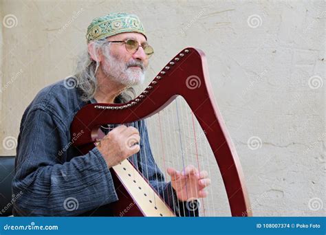 Old musician playing harp editorial stock image. Image of artist - 108007374