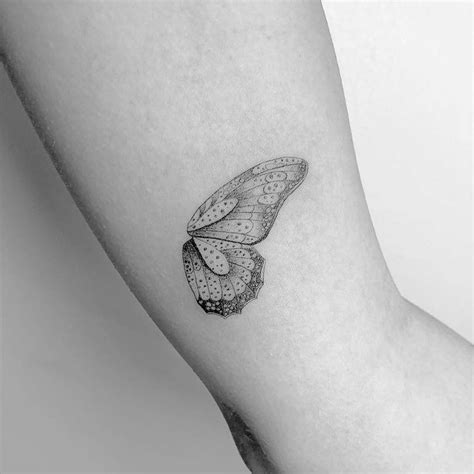 Butterfly wing tattoo on the left inner arm.