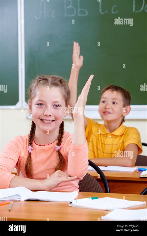 Portrait of lovely girl raising hand at workplace with schoolboy on background Stock Photo - Alamy