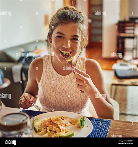 Happy as long as Im not hungry. Shot of a young woman eating food at the dining room table at ...