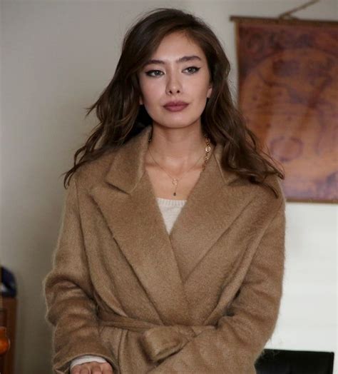 a woman in a brown coat standing next to a lamp