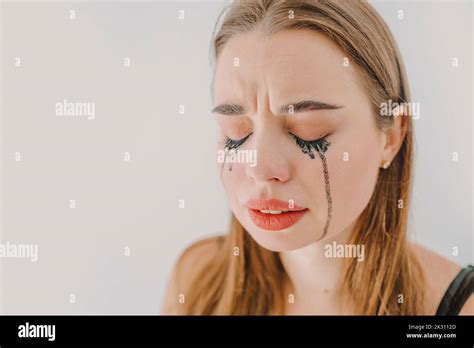 Sad young woman with smudged mascara crying in front of wall Stock ...