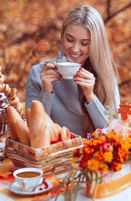 a woman sitting at a table with a cup of coffee in her hand and autumn ...