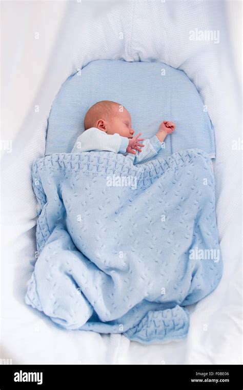 Newborn baby boy in bed. New born child sleeping under a blue knitted ...