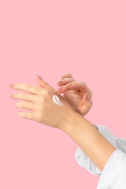 Premium Photo | Female hands on a pink background smear cream long beige nails manicure and gel ...