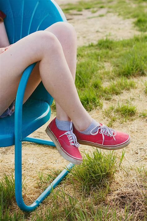 Side image of teen with legs crossed over arm of chair by Tana Teel ...