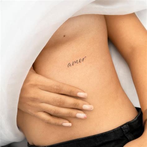 "Amor" lettering tattoo handwritten on the rib.