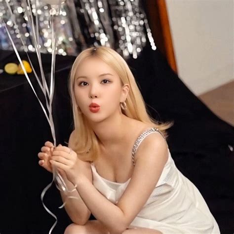 a woman sitting on the floor with some balloons in her hand and wearing a white dress