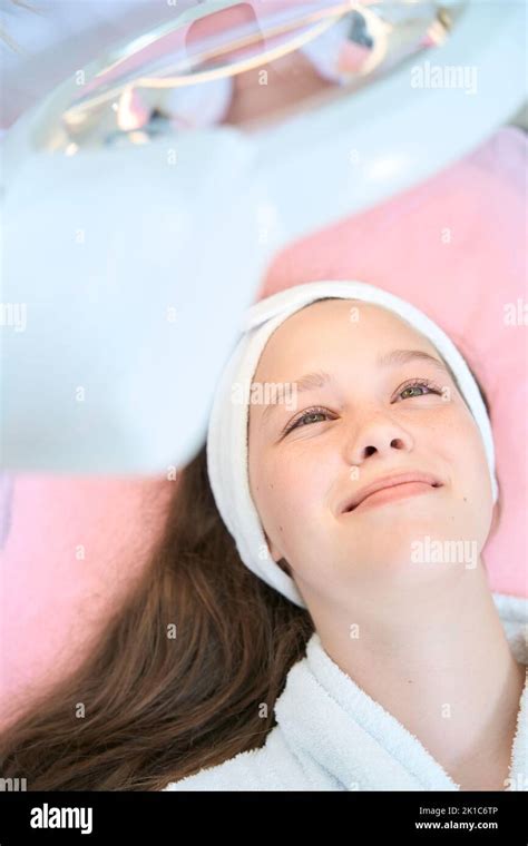Photo of face of smiling girl lying under magnifying lamp Stock Photo ...