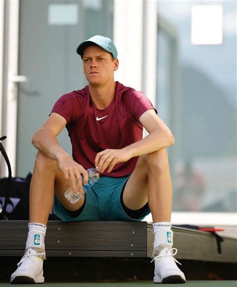 a man sitting on a bench with his tennis racket and water bottle in hand