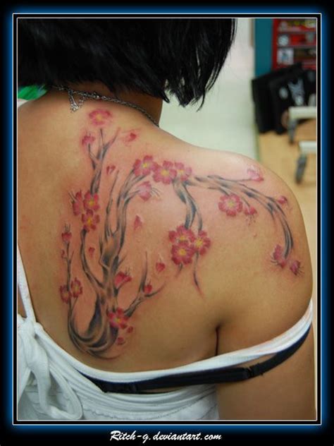 the back of a woman's shoulder with pink flowers on it and branches in bloom