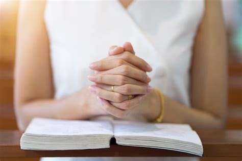 Mãos da mulher que rezam em uma bíblia sagrada na igreja para o ...