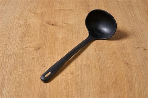 Premium Photo | A black spoon on a wooden table with a black handle.