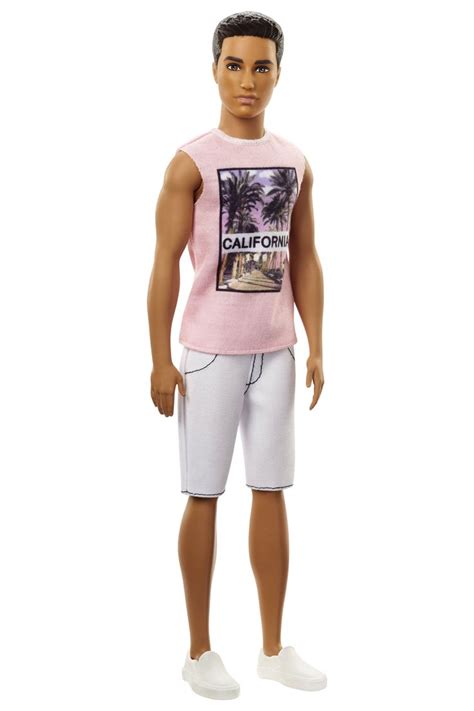 a male doll wearing a pink shirt and white shorts with palm trees in the background