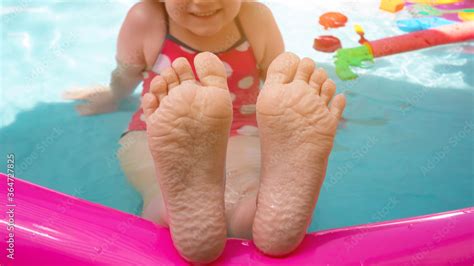 Kids feet laying on colorful rainbow inflatable swimming pool. Young ...