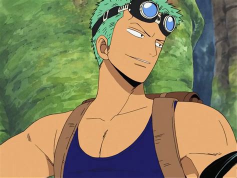 a man with green hair and goggles in front of some trees, looking at the camera