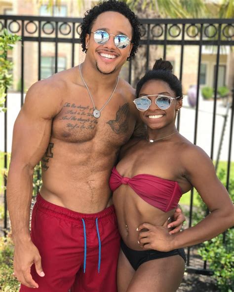 a man and woman in swimsuits standing next to each other near a fence