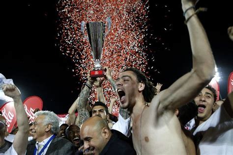 Players of Apollon, Limassol, hold the trophy aloft after their victory against AEL during the ...