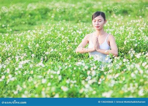 Young Lady Doing Yoga Exercise in Green Field with Small White Flowers Outdoor Area Showing Calm ...