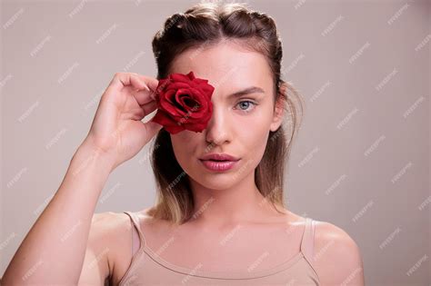 Premium Photo | Beautiful young woman covering eye with red rose bud ...