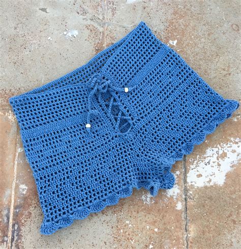 a blue crocheted cloth laying on the ground next to a tile floor with holes in it