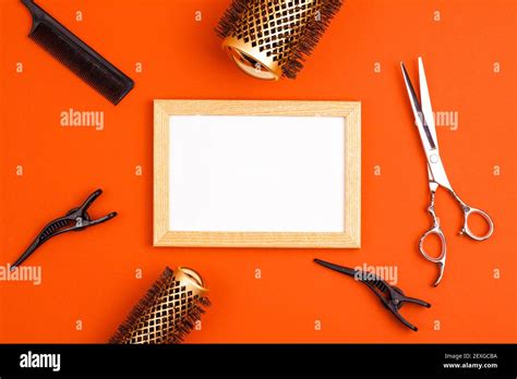 Mockup wooden frame flat lay of professional hair cutting shears, gold round hair brushes for ...