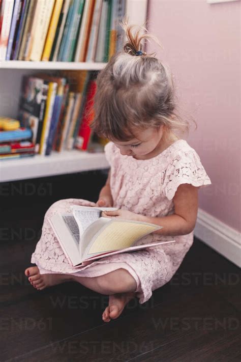 Girl sitting on playroom floor reading book stock photo