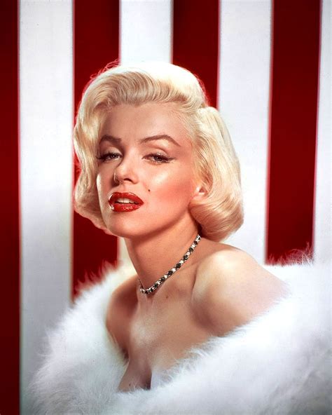 a woman with blonde hair wearing a white fur collar and choker necklace, in front of an american ...