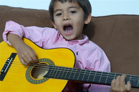 kid-singing-playing-classical-guitar – Children in Homes Music Lessons