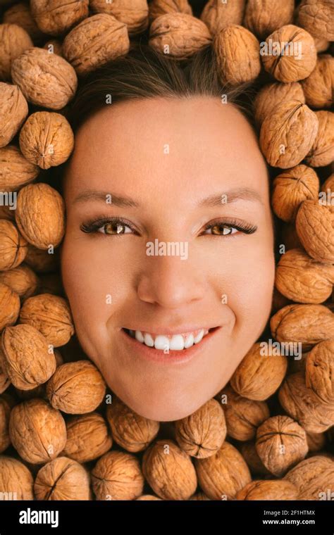 Woman smiling face on a walnuts background. Eating nuts. Strong teeth ...