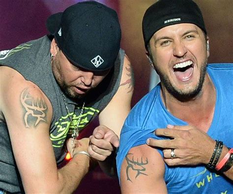 Jason Aldean (left) and Luke Bryan show off their matching tattoos during a performance at ...