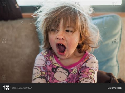 Little girl with bedhead yawning stock photo - OFFSET