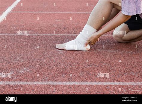 Male athlete applying compression bandage onto ankle injury of a ...