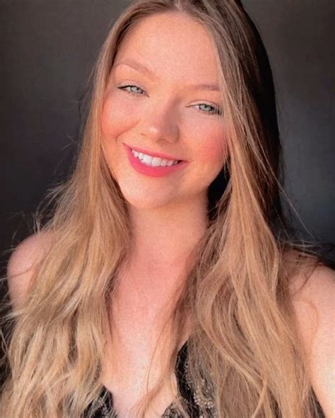 a woman with long blonde hair smiling at the camera