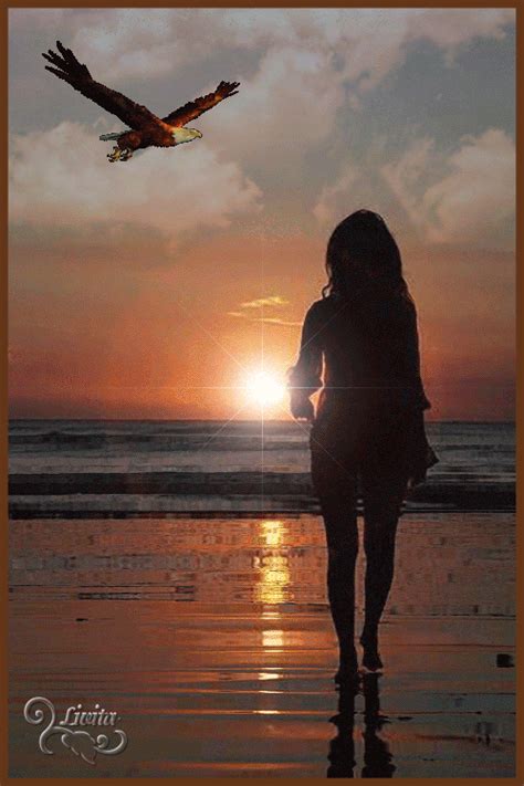 a woman is walking on the beach with an eagle flying over her head at sunset