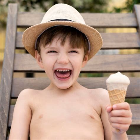 Niño sonriente con sombrero comiendo helado | Foto Gratis